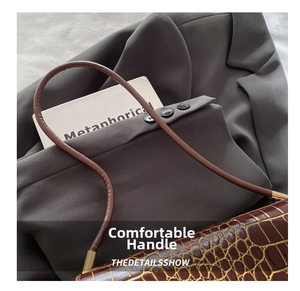 Macro shot of brown crocodile pattern handbag with glossy finish and gold metal hardware