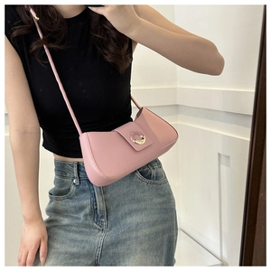 On-body view of a small pink crossbody bag with a gold ring buckle and leather strap