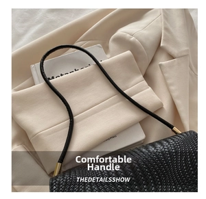 Close-up of the woven black handle with gold metal accents on a stylish handbag