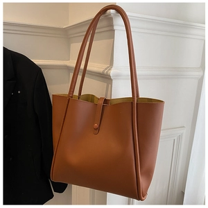 Brown minimalist tote bag hanging next to a suit jacket showing spacious interior design