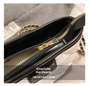 Close-up of golden zipper and quilted white leather detail on luxury shoulder bag