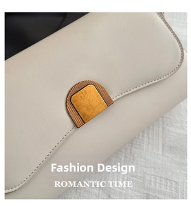Détail macro du fermoir doré vintage sur un sac à bandoulière en cuir crème chic