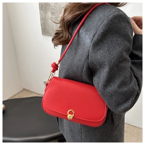 Detail der roten Ledertasche mit goldenem M-Schloss und dekorativem Knotenelement am Gurt
