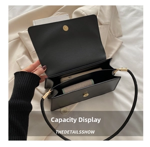 Detail view of double compartments in a black faux leather shoulder bag with gold hardware