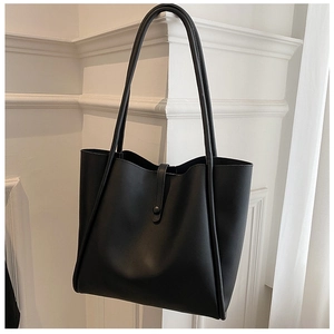 Close-up of matte black leather tote bag with buckle closure and long shoulder straps