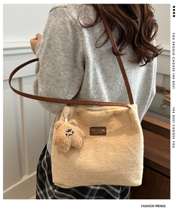 Detail of beige plush tote bag with brown leather strap and mini teddy bear charm
