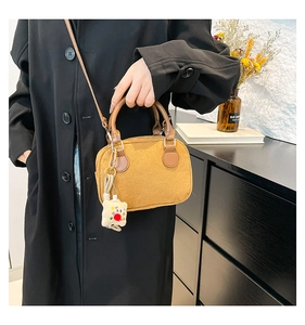 Macro view of velvet boston bag with plush doll charm and brown round handles