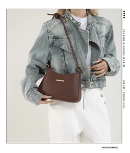 Close-up of brown matte shoulder bag with gold hardware on a denim outfit model