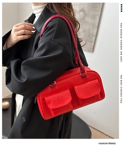Detail of red crocodile texture handbag with dual front pockets and silver ring buckles