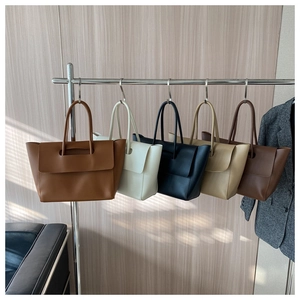 Group of minimalist leather tote bags in various colors on a display stand