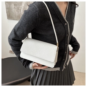 Detail of white minimalist shoulder bag showing woven texture and gold hardware accents