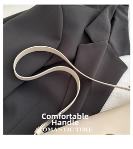 Détail de la bandoulière en cuir blanc crème aux bords lisses sur un blazer gris