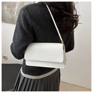 Detailed view of white crocodile embossed baguette shoulder bag on a model