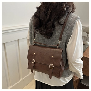 Detail of vintage brown backpack with buckle straps and embossed lucky logo on the flap
