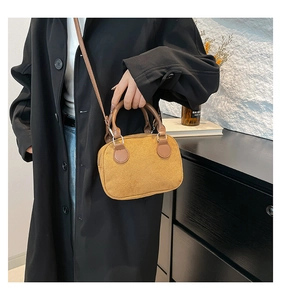Detail of yellow suede velvet pillow bag worn over a black coat with metal zip