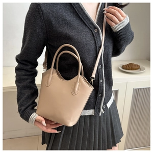 Lifestyle shot showing the scale of a nude minimalist bucket bag on a model's shoulder