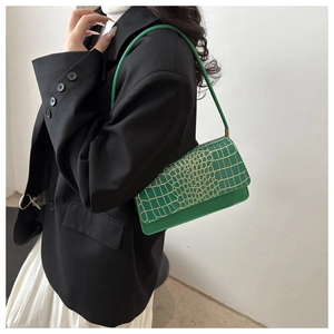 Detailed view of green crocodile pattern handbag with elegant gold hardware accents