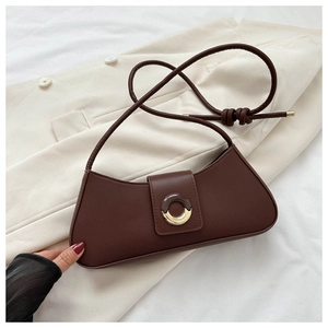 Detail of dark brown leather underarm bag with unique brown and gold circular hardware