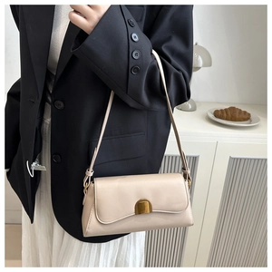Détail d'un sac baguette crème avec un fermoir doré demi-lune au design rétro élégant
