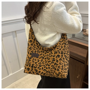 Detail view of stylish leopard print corduroy tote bag worn by a model in a cozy setting
