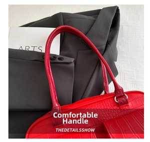 Macro detail of red tote bag featuring crocodile skin texture and sturdy dual handles