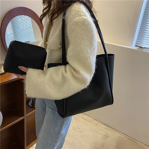 Black minimalist faux leather tote bag and pouch set displayed on shoulder by model