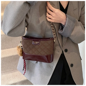 Detail of quilted leather bucket bag with gold chain strap and plush ball pendant