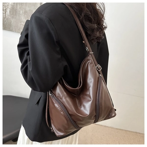 Detail of soft dark brown leather tote bag with decorative side metal zippers and sleek finish