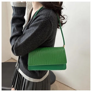 Detail of green baguette bag featuring woven texture and smooth faux leather finish