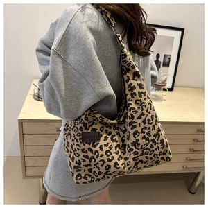 Detailed macro view of leopard print corduroy tote bag featuring a leather fashion label