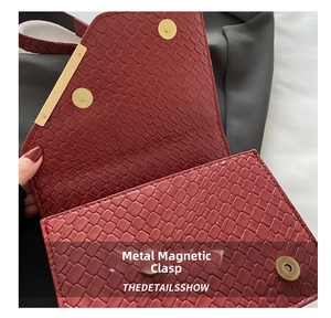 Détail du sac en cuir gaufré rouge montrant le fermoir magnétique doré et la texture