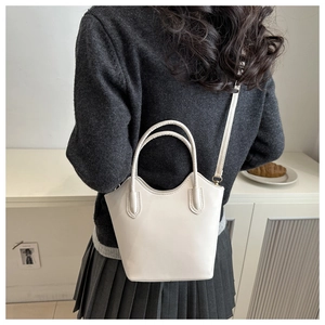 Detail of minimalist off-white bucket bag shown on person for size and style reference
