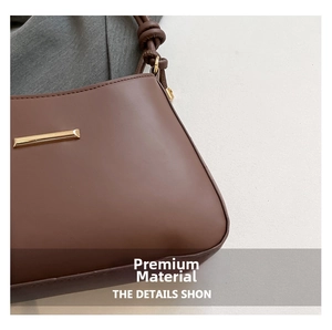 Close-up of brown matte leather shoulder bag with gold metal trim and knotted strap detail