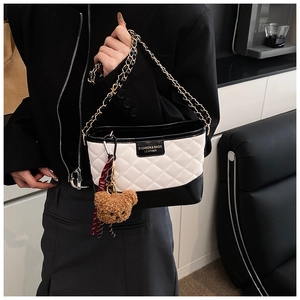 Detail of color-block quilted hobo bag with gold chain and plush bear charm