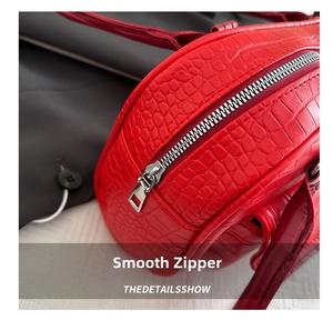 Macro detail of red crocodile pattern leather bag featuring a smooth silver metal zipper