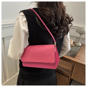 Rose pink baguette shoulder bag with woven texture detail worn by a model in lifestyle setting
