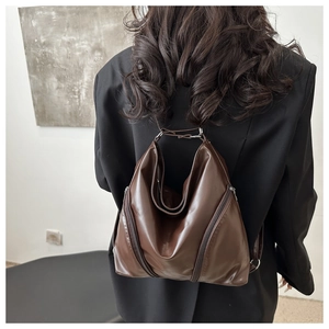Detail of dark brown soft leather tote showing side zippers and sleek triangular structure