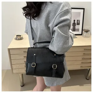Detail of a vintage black leather crossbody bag featuring metal buckles and a top handle