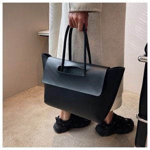 Modern minimalist black leather tote bag shown in a professional lifestyle setting