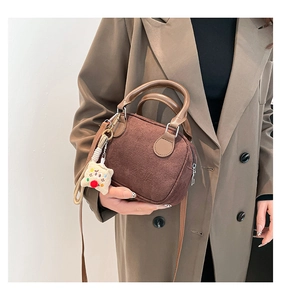 Detail of vintage brown bowling bag with plush charm and detachable crossbody strap