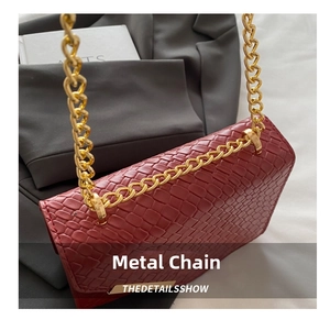 Détail de la texture tressée rouge et de la grosse chaîne dorée sur le sac bandoulière chic