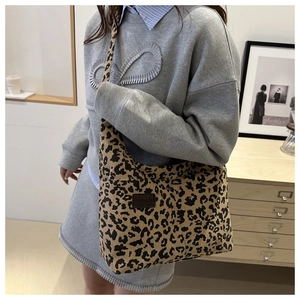Detail of leopard print corduroy tote bag featuring a leather patch and striped texture