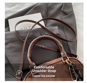 Detail der Wildleder-Handtasche mit bequemen Lederriemen und dekorativem Webanhänger