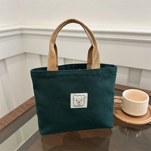 Dark green canvas handbag with brown woven straps and a cute white bear patch