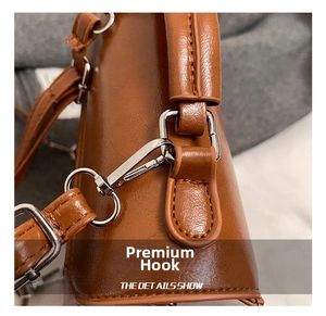 Dettaglio del gancio in metallo argento e cuciture sulla borsa tote in pelle cerata marrone