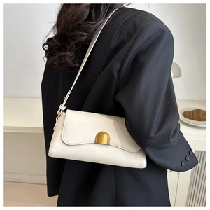 Detail of white leather baguette bag with gold metal clasp worn by a model in a minimal setting
