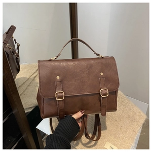 Detail of vintage brown leather backpack with gold buckle and embossed lucky text