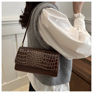 Détail du sac à bandoulière marron foncé en relief crocodile avec finitions dorées