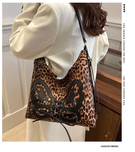 Detail of leopard print tote bag featuring black butterfly applique and lace-up accents