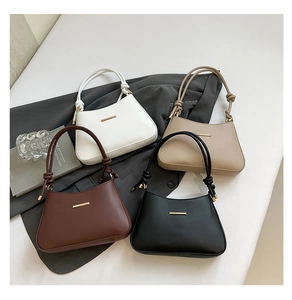 Flat lay of minimalist crescent underarm bags in four colors with knot detail and gold trim